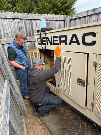 Two technicians servicing a Generac standby generator Two technicians servicing a Generac standby generator